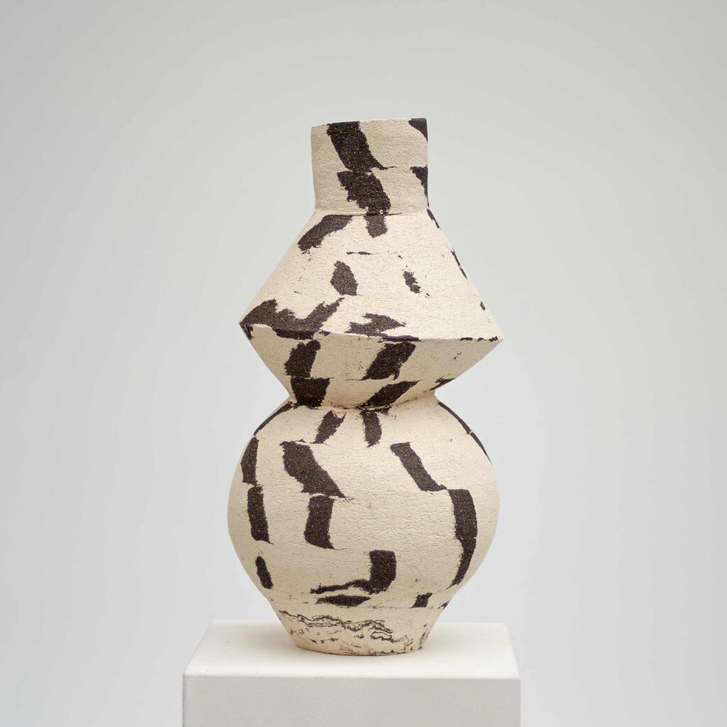 <em>DUOTONE</em> Vase, schwarz und weiß, mit rundem Boden und geometrischer Form darüber. 17 x 16 x 33 cm.